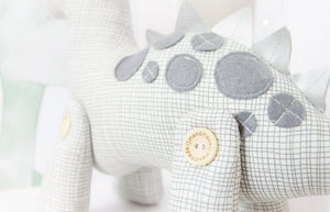 RubyBabyDesigns Keepsake Collective Heirloom Cloth Duke the Dinosaur Keepsake decor. White base with grey etched print, with co-ordinating grey felt spots, and silver faux leather dinosaur spines. Bought to life using environmentally friendly PET fill and wooden buttons on his legs. Designed and handmade in Melbourne.