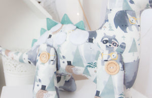 RubyBabyDesigns Heirloom Cloth Decor Duke the Dinosaur, featuring lovely faux leather spines in a seafoam teal, with white wool felt applique spots on his back. His print is a gorgeous watercolour print of blues, navys, seafoams and mochas and features bears, woodlands, mountains and racoons. Filled with environmentally friendly PET fill and jointed together using engraved handmade wooden buttons.Handmade in Melbourne. 