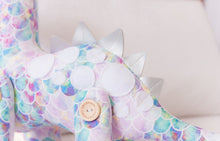 Load image into Gallery viewer, RubyBabyDesigns Keepsake Collective Daisy the Dinosaur, created using mermaid scale watercolour inspired print, jointed in design with handmade engraved wooden buttons, featuring white felt circles on back and faux leather dino spines on her back. Filled with environmentally friendly PET Fill. Handmade in Melbourne. 