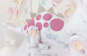 RubyBabyDesigns Keepsake Collective Heirloom Luxe Cloth Dinosaur Keepsake, created with luxurious digital printed cotton. Faux leather in a champagne colour for back spines, and wool blend plum toned felt as applique spots. Stuffed with premiun PET fill and handmade and designed in melbourne. Featuring a soft watercolour digital floral print on the body with soft pinks, maroons, plums, greens and blues on a white base. 4 engraved wooden buttons on jointed legs. Heirloom Cloth Decor keepsakes.